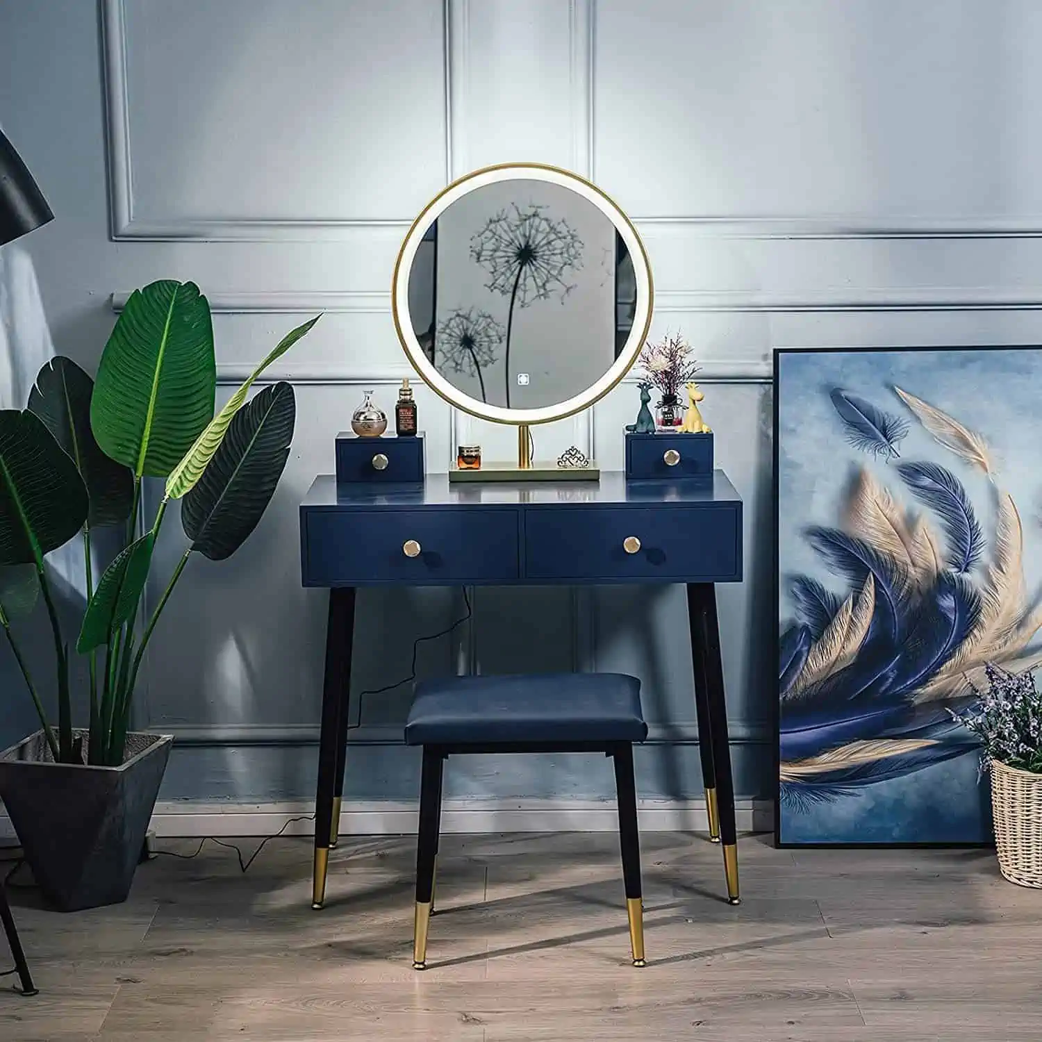 An elegant blue-colored dresser with a round mirror, ring light, minimum storage, and a matching stool, in a white well-decorated room.