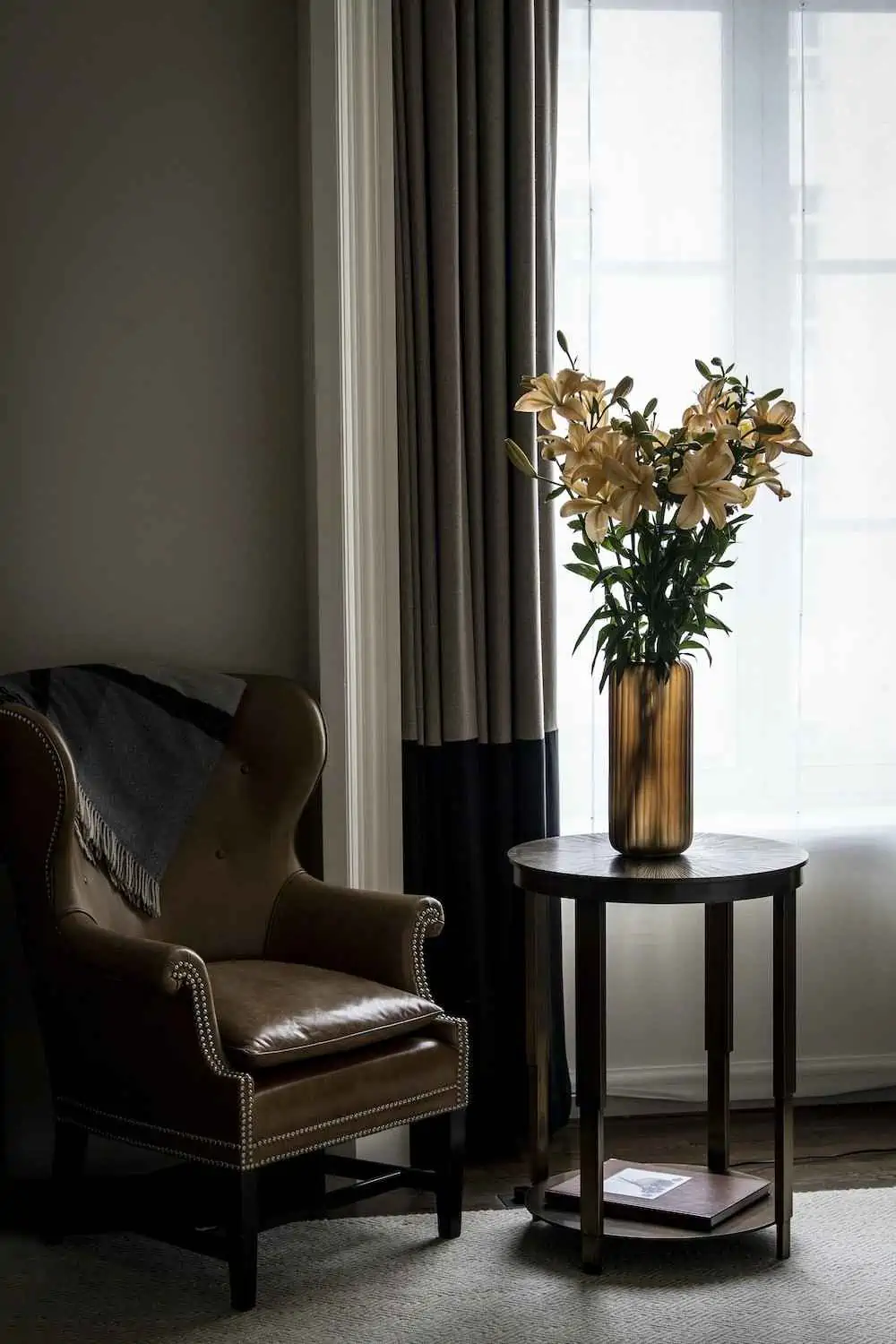 yellow lily flowers in a vase with a chair and table