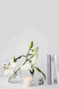 White lily flowers in a glass vase with green foilage