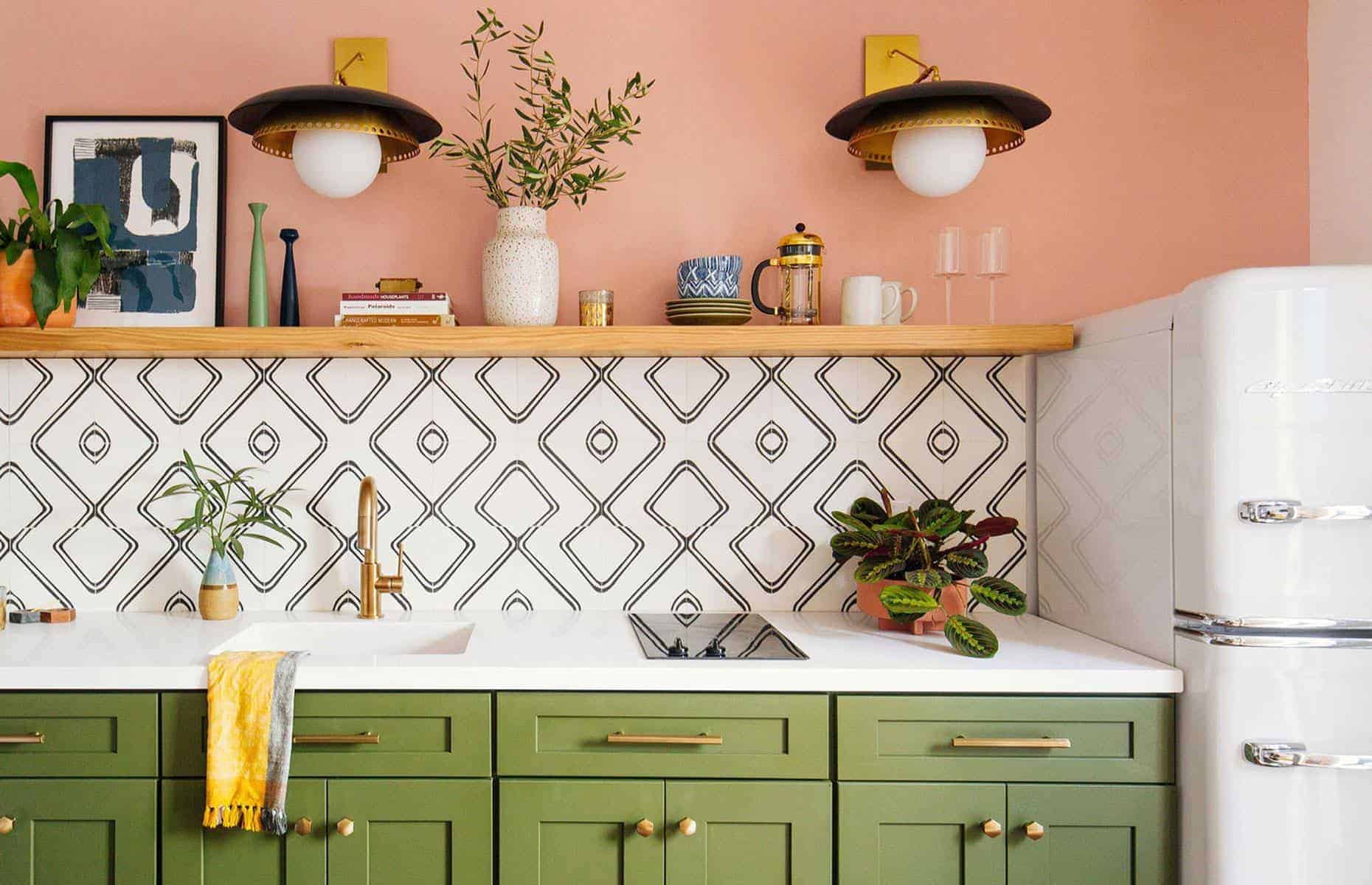 patel pink walls with black and white geometric tiles and green cabinets in the kitchen