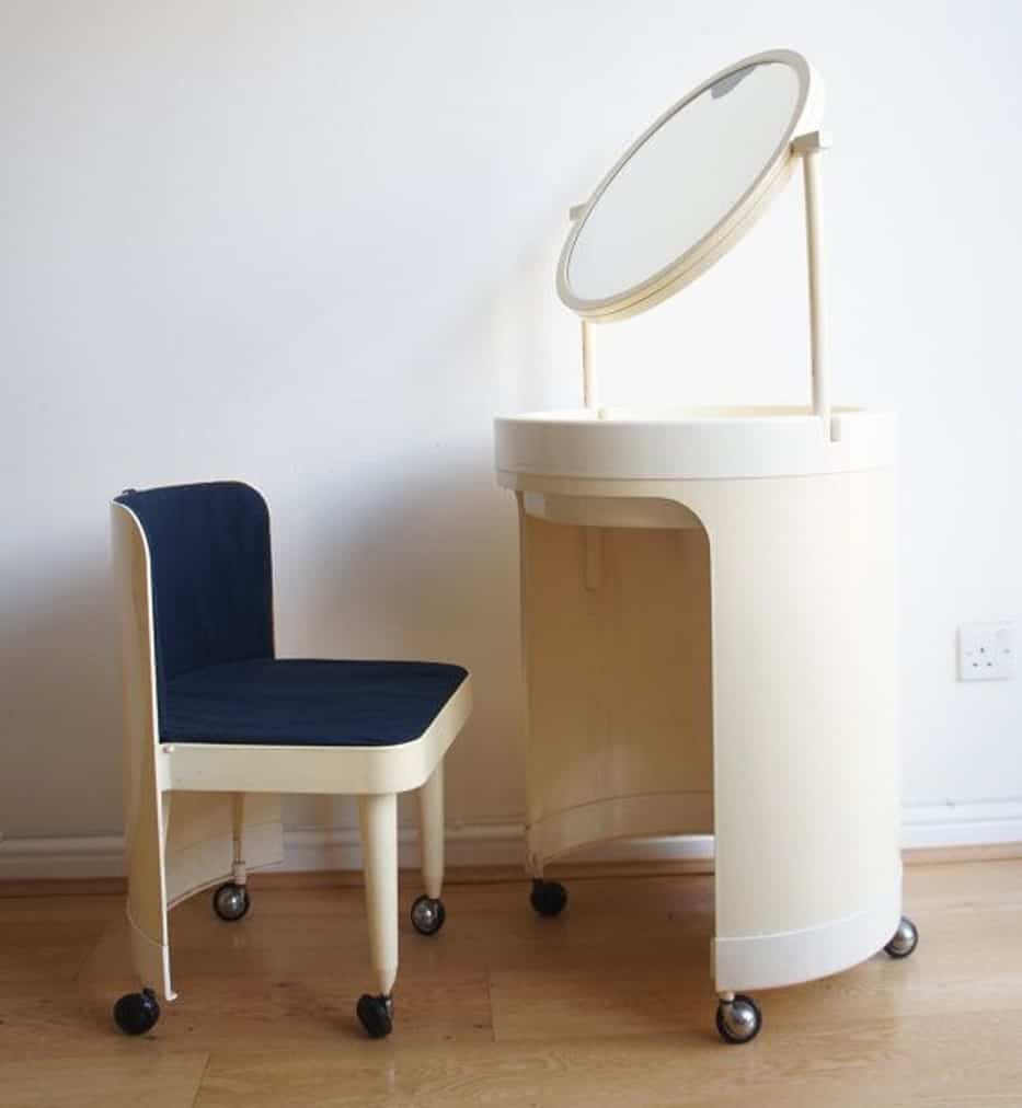 A plastic vanity with a round mirror, minimum storage, and a matching chair, in a white room.