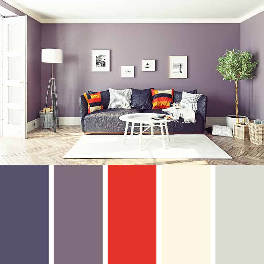 A living room with purple walls, blue couch and red cushions