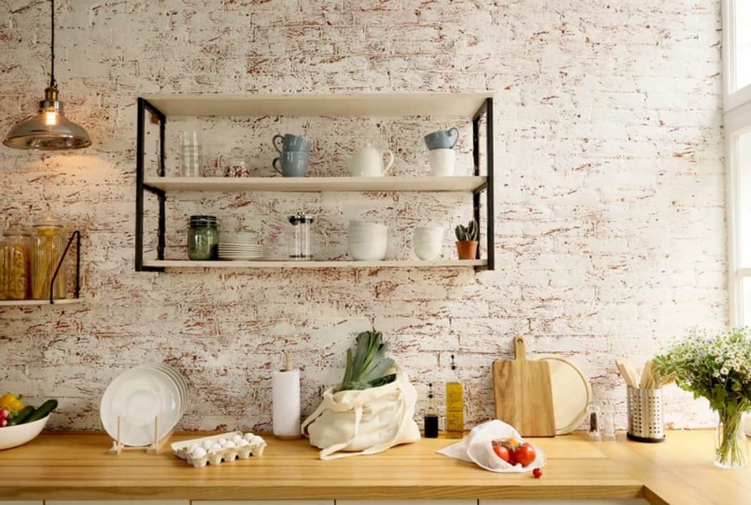 white kitchen wall with red specks and brown counters with a floating shelf