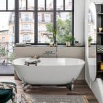 white freestanding bath tub in front of a huge window with glass inserts