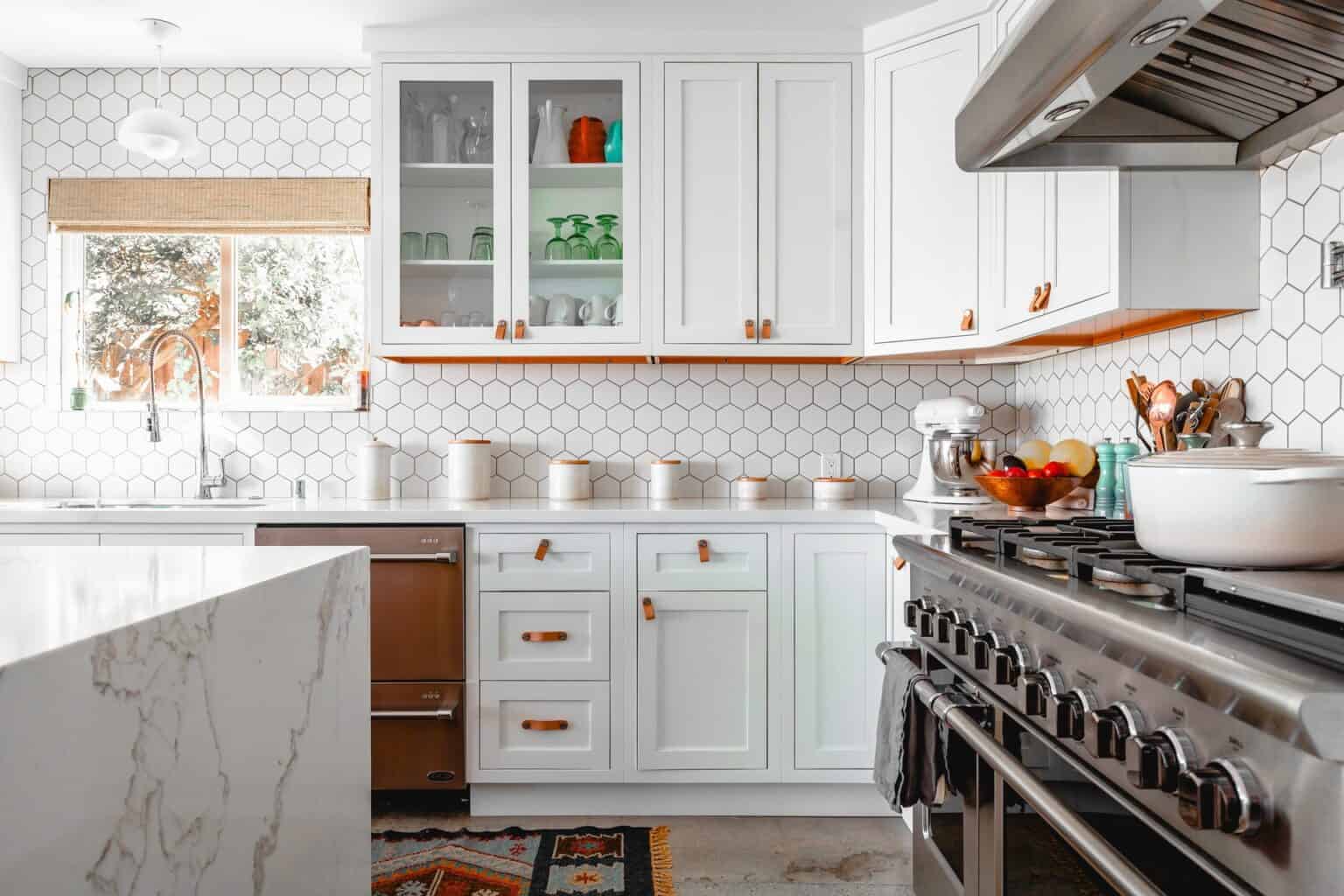 A pretty white-colored wall kitchen cabinet in a white-tiled kitchen.