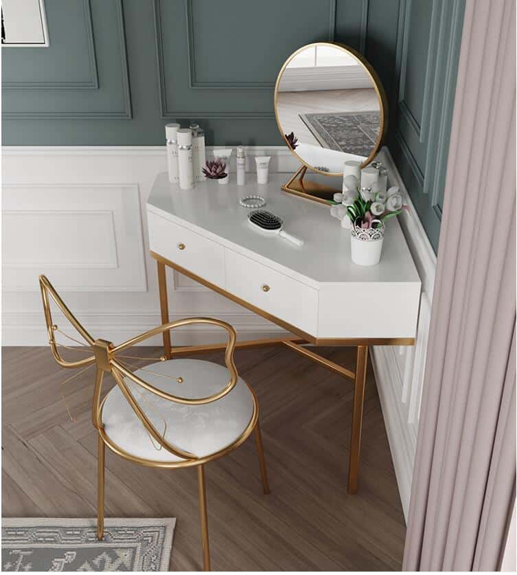 A pretty white-color corner dressing table design with a golden-framed round mirror and drawers.