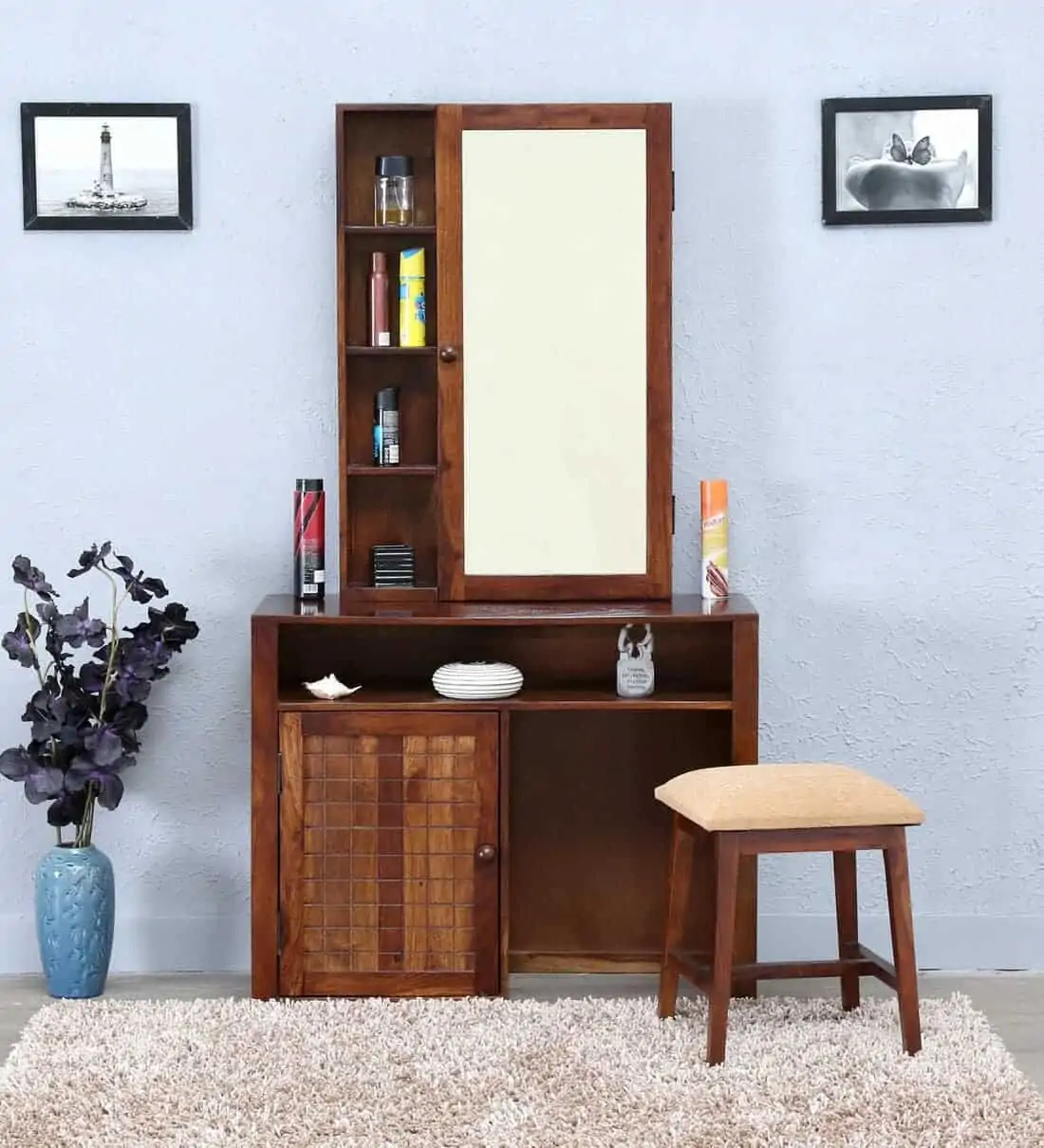 A beautiful wooden vanity with a rectangular mirror, good storage space, and a matching stool, in a blue-colored room.