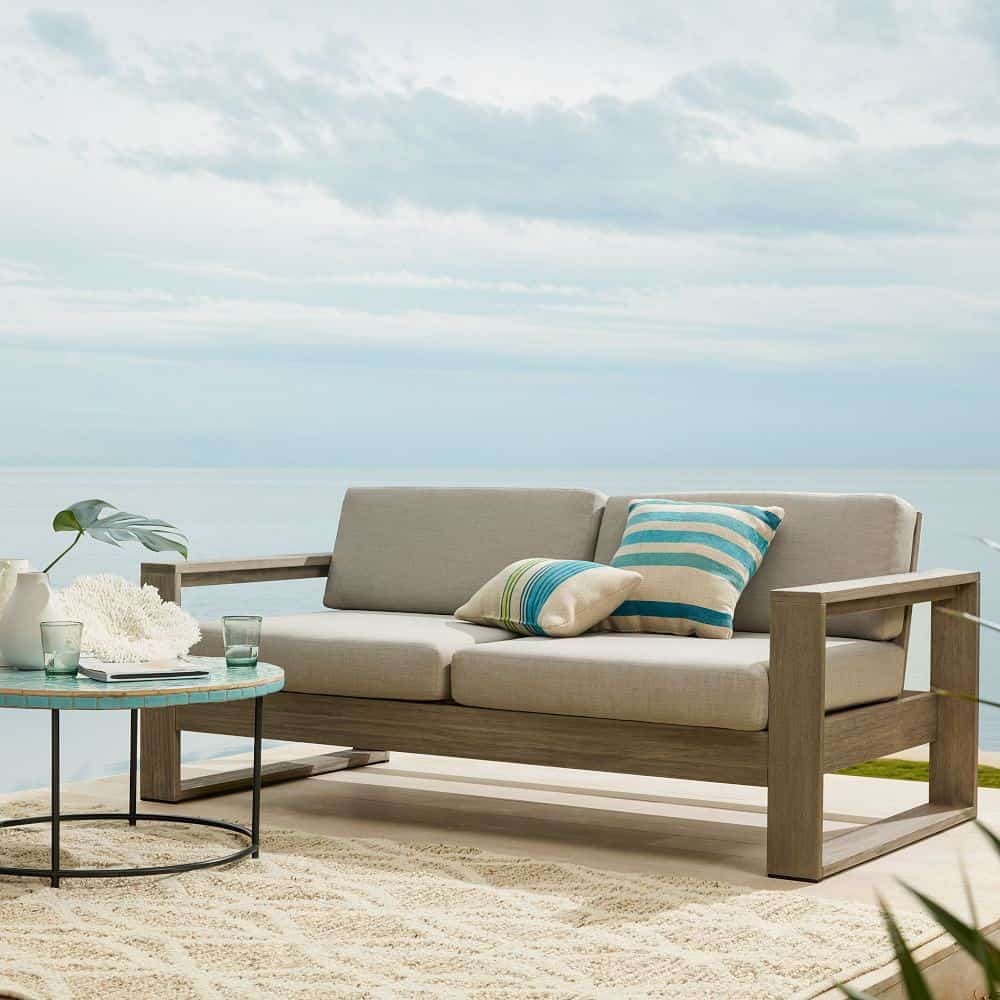 sofa set placed outside with soothing blue sky and beige coloured rug