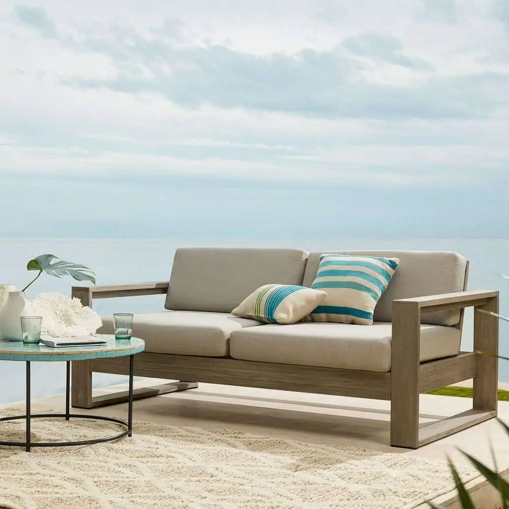 sofa set placed outside with soothing blue sky and beige coloured rug