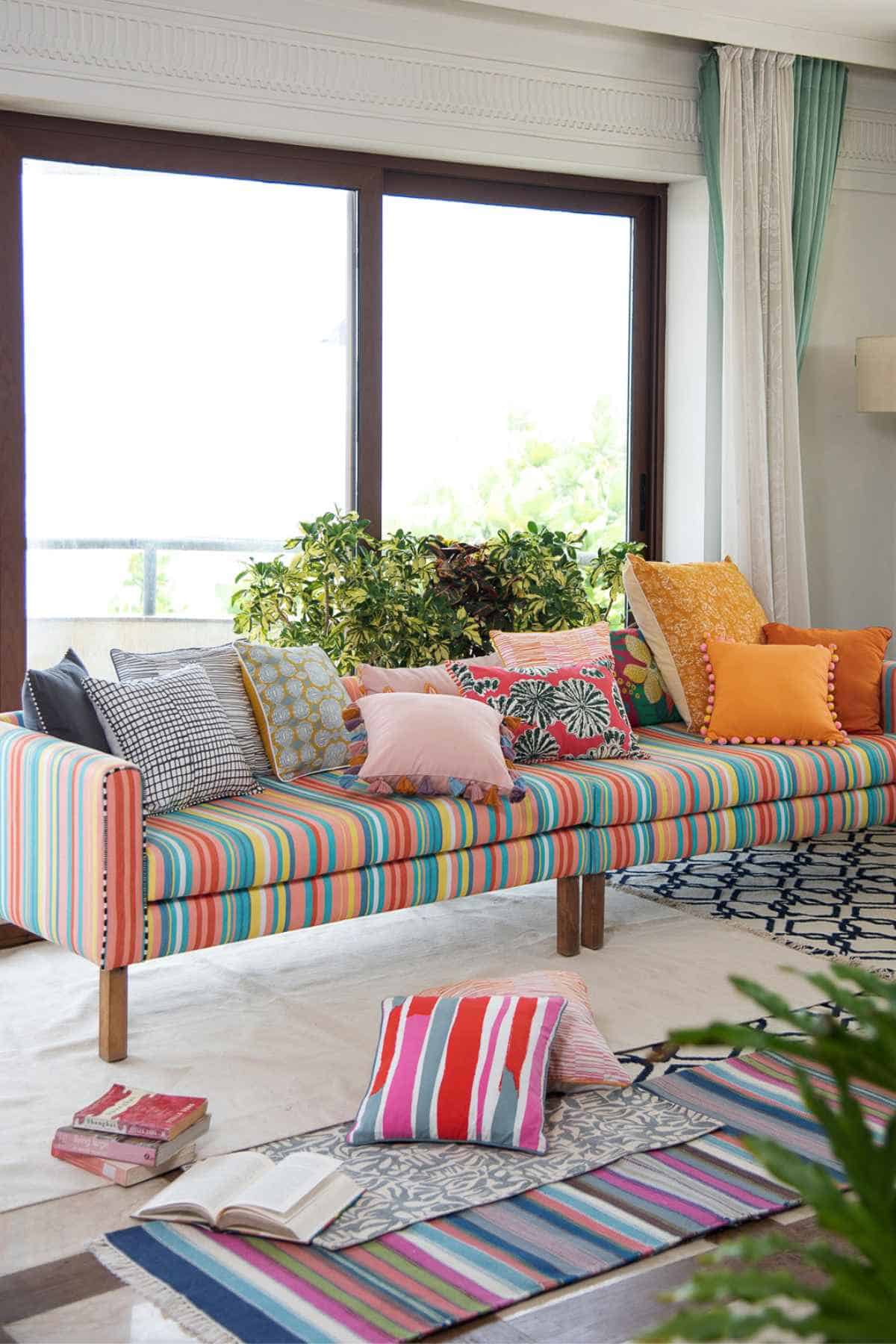 multicolored sofa in a living room with rugs and a window view