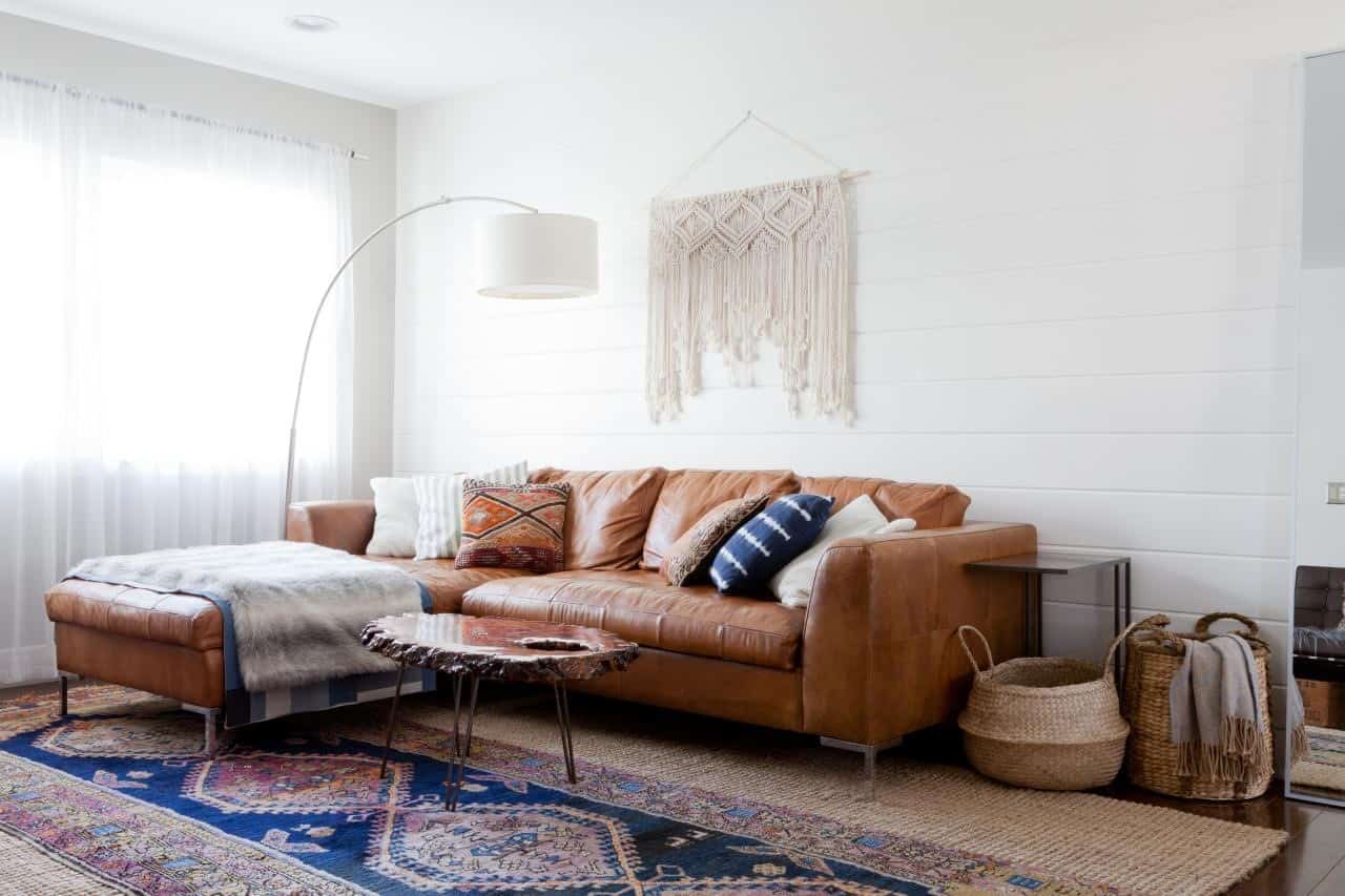 white walls in a living room with brown sofa with multicolor rug and curtains