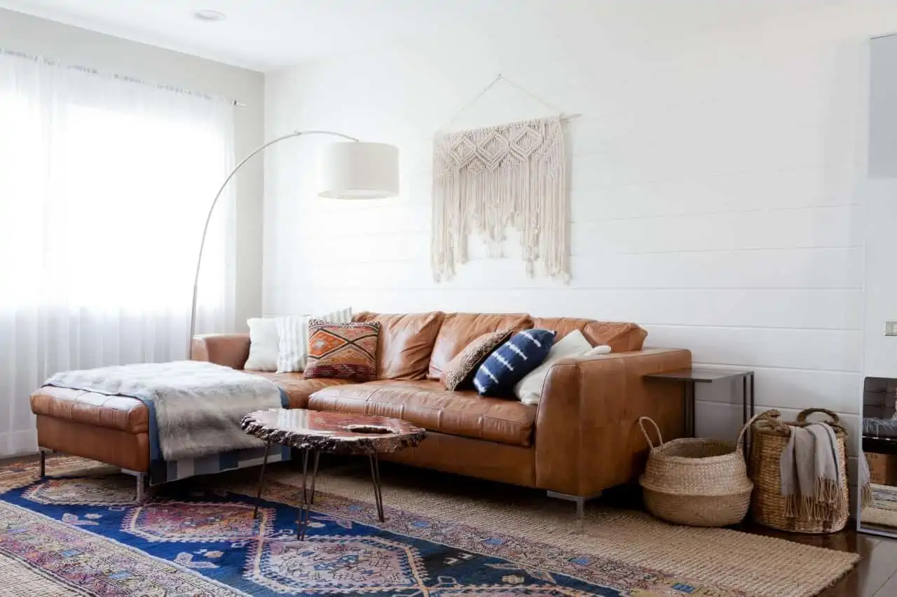 white walls in a living room with brown sofa with multicolor rug and curtains