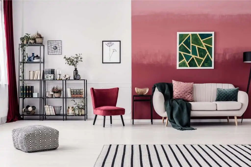 color coded wall with white sofa, red chair, rug and a shelf