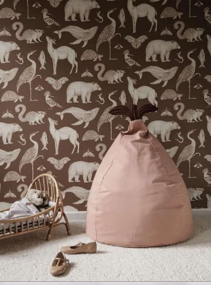 light pink beanbag in nursery with brown animal print wallpaper