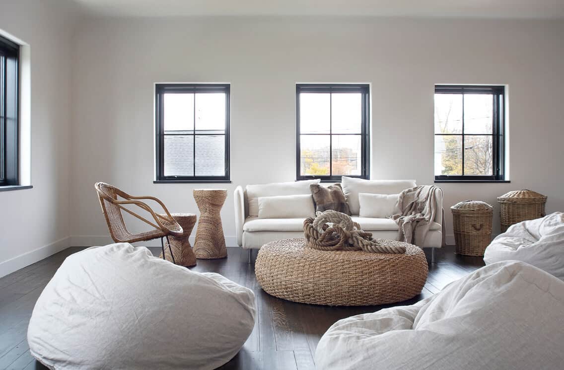 light grey bean bag chair in this modern setting with a white sofa and a rattan coffee table