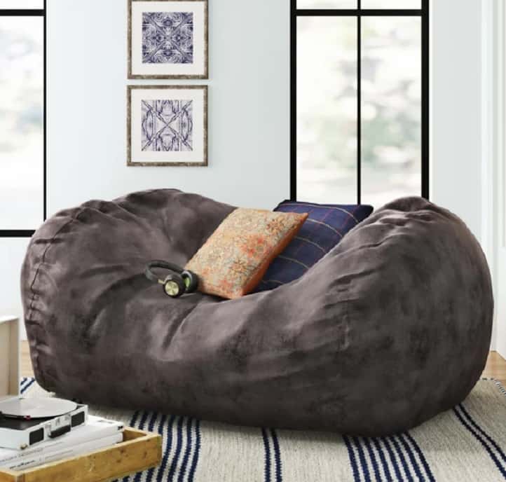 Giant bean bag chair in black with a striped carpet and beige cushion