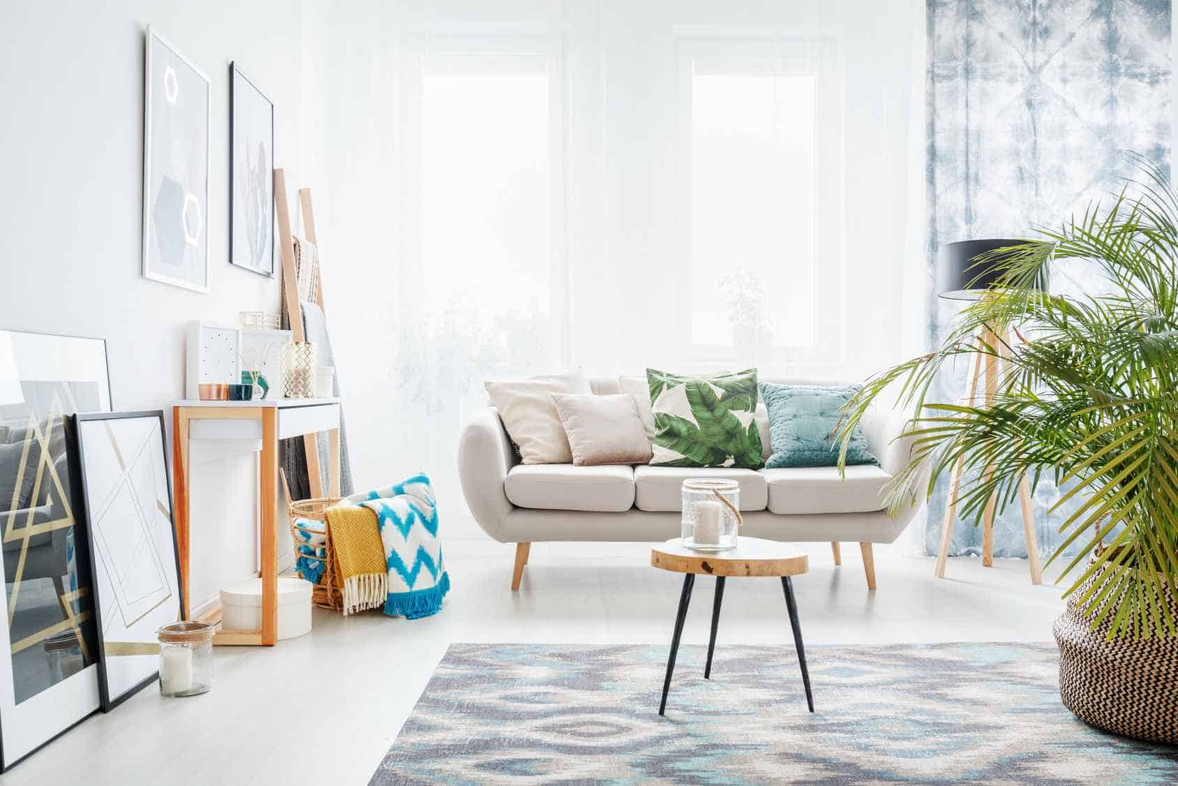 white sofa in a living room with rug, table, mirror, plant