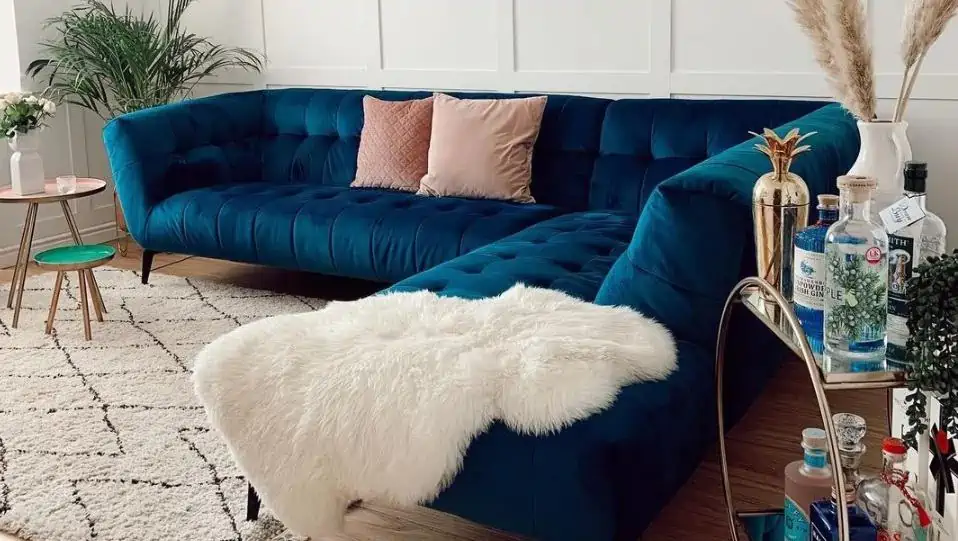 blue velvet couch with white fur throw and light pink cushions