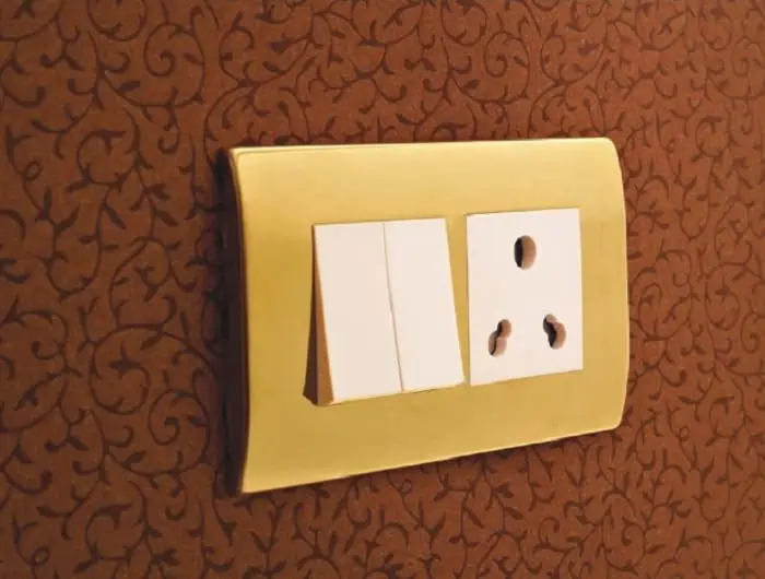 gold and white types of electrical switches on red wallpaper