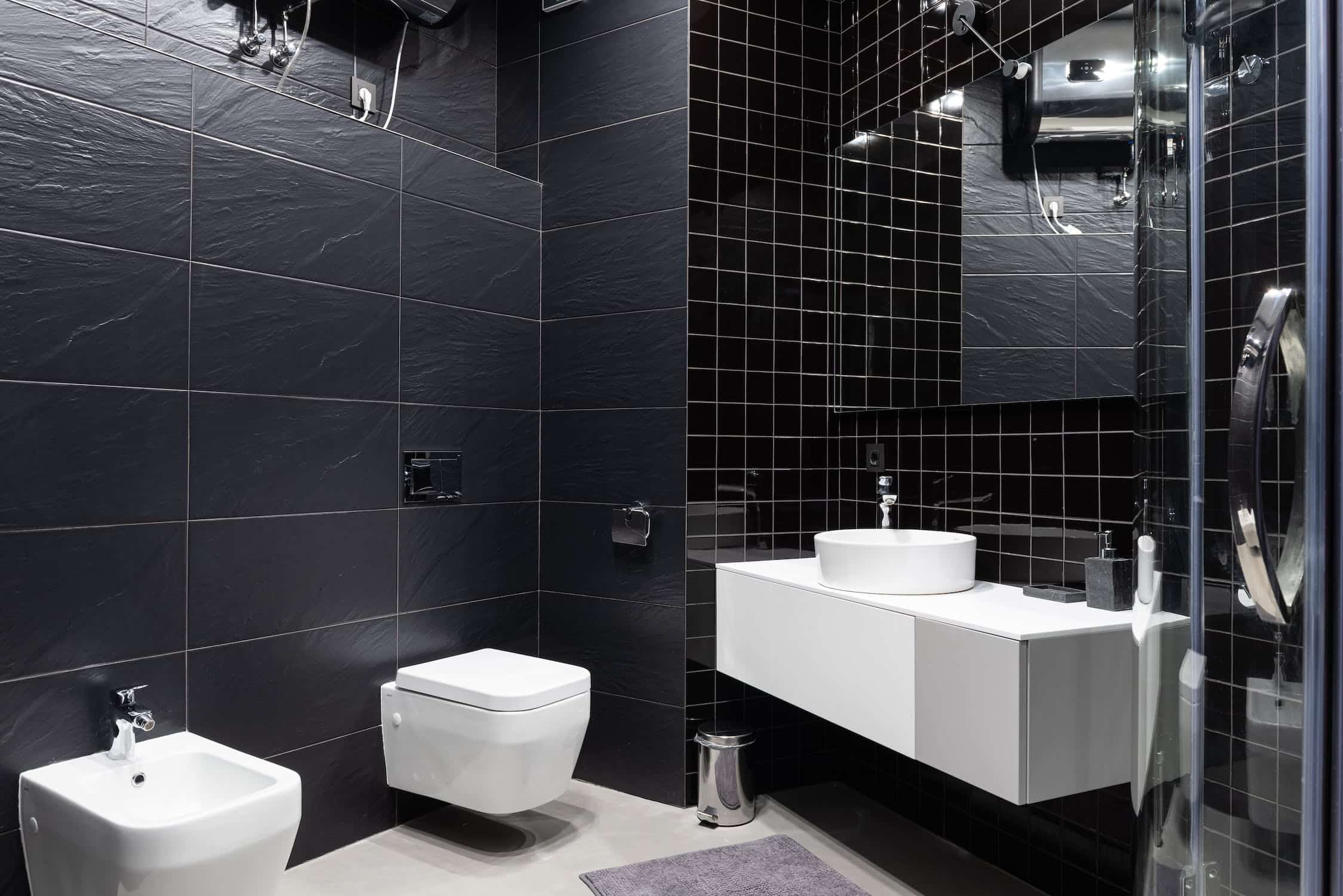 all black bold compact restroom, floating water closet, mirror, tiles
