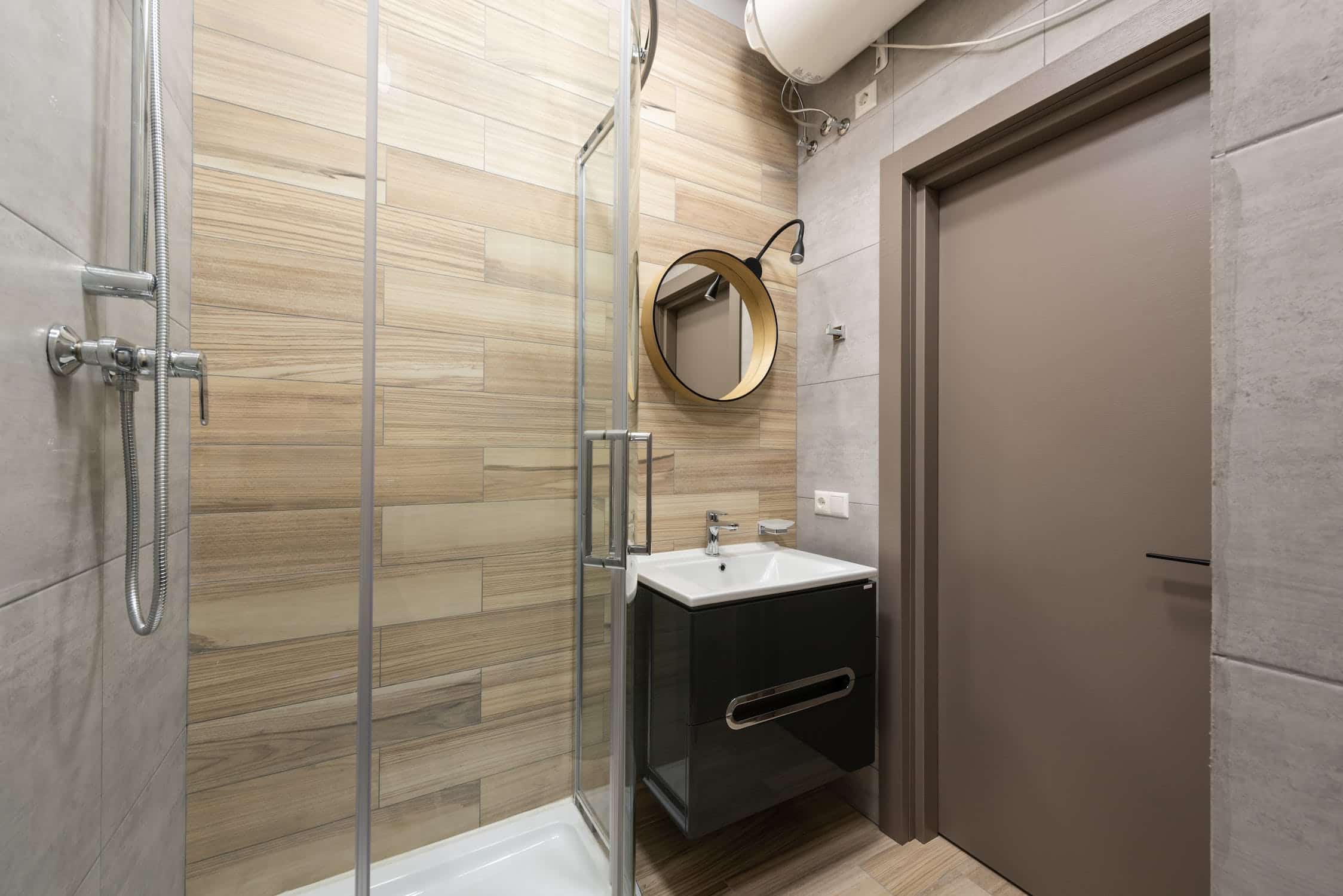 compact bathroom with built-in vanity, mirror, wall sconce, glass door, shower cubicle