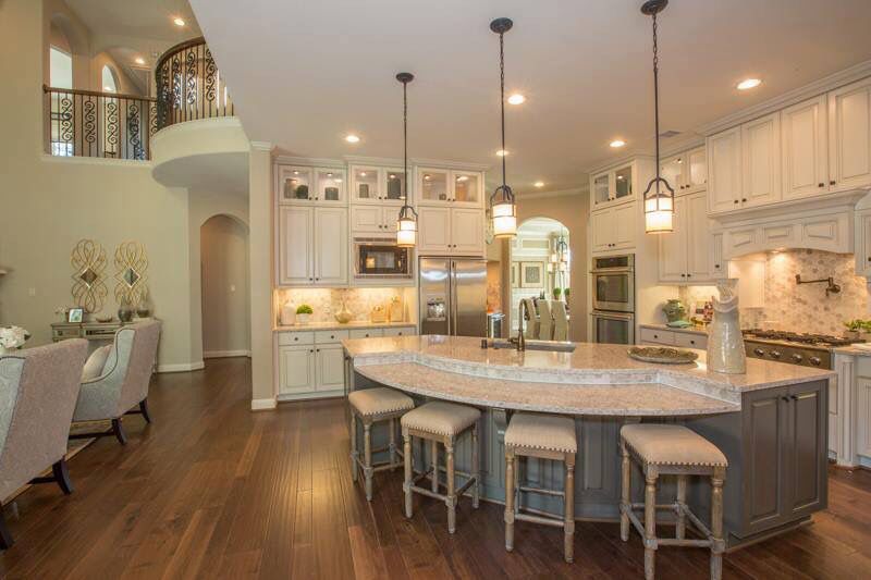 kitchen island with curved marble top, in-built sink, hanging lights over the island, white walls, stools installed around the island