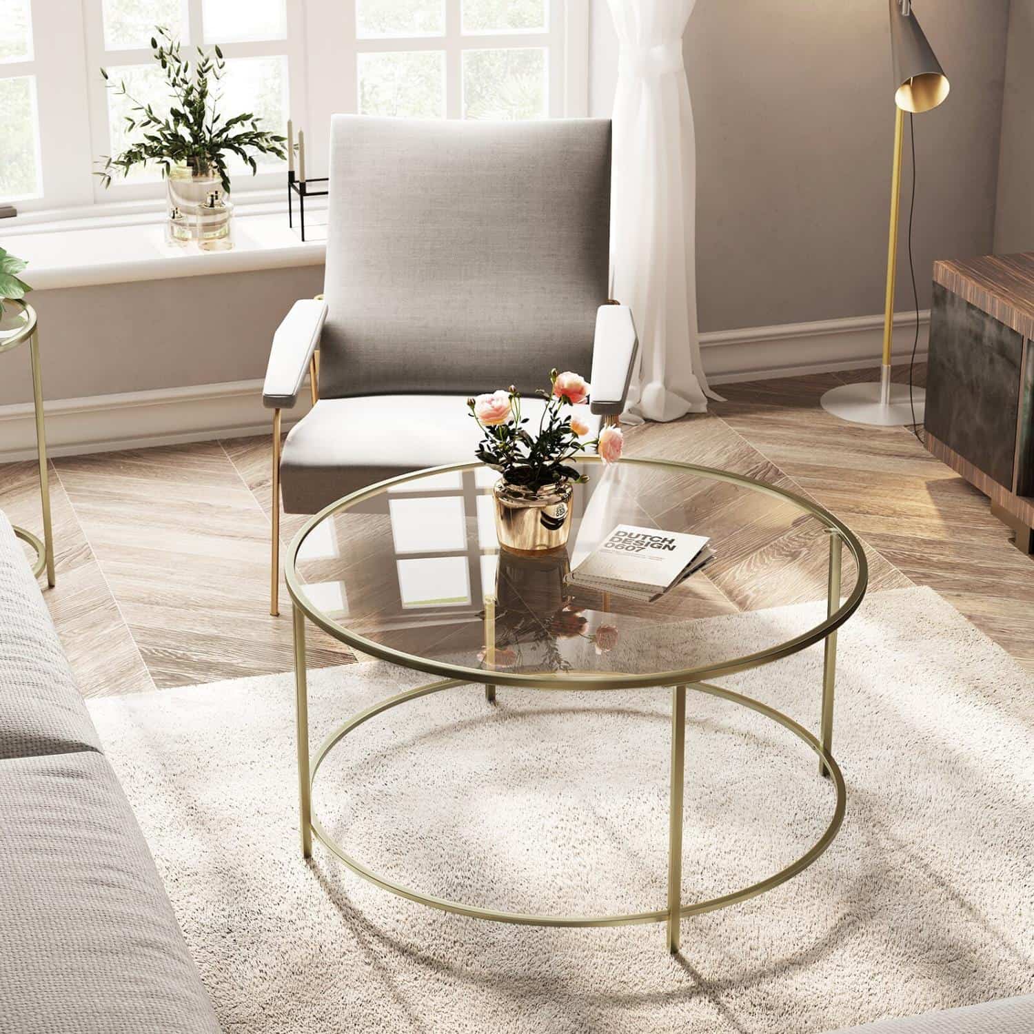 sleek round glass centre piece with gold imitation, flower arrangement, grey sofa, carpet, floor, reading lamp in the corner