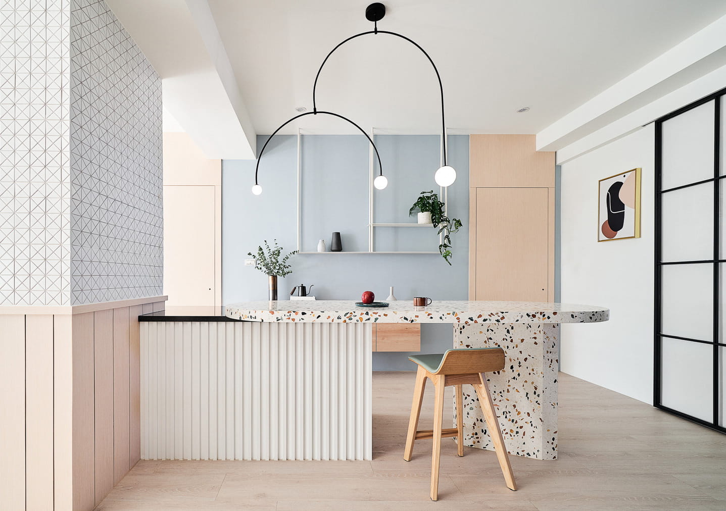 open plan living room with cooking space with pastel colour scheme, stained marble countertop, blue-pink pastel coloured walls, wooden stool, task lighting using bulb, wooden stool