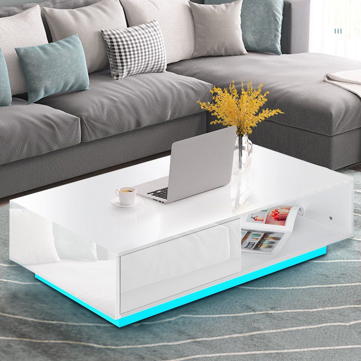 centre piece with high gloss finish, in-built LED light, side shelves for storage, grey sofa, cu،ons, carpet on floor, laptop on table top, living room, decorative piece