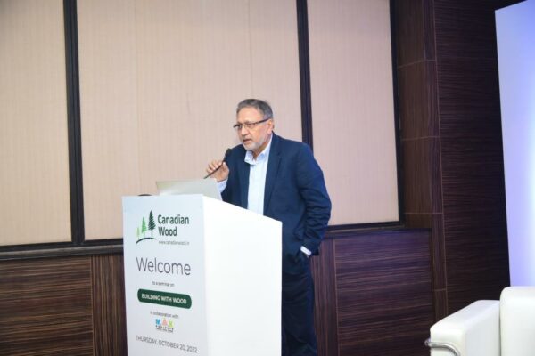 Pranesh Chhibber at the Dias in an educational Seminar on building with wood placed on a white table including engineered wood used to build sustainable villa using wood frame construction