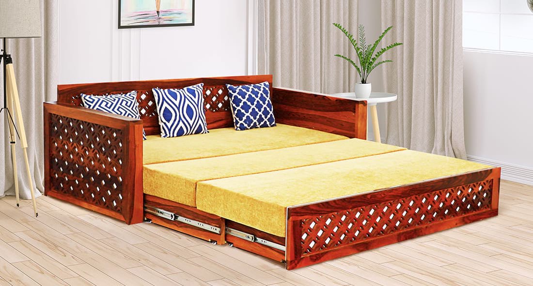 royal wooden sofa cum bed, yelloow mattress, royal blue cushions, beige walls, curtains, white side table, plant placed on table, wooden laminated floor, beautiful bedroom