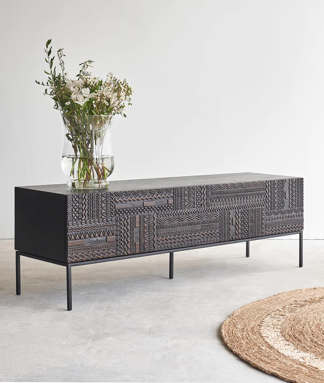 carved television stand and console table, planter placed on it, rug on floor
