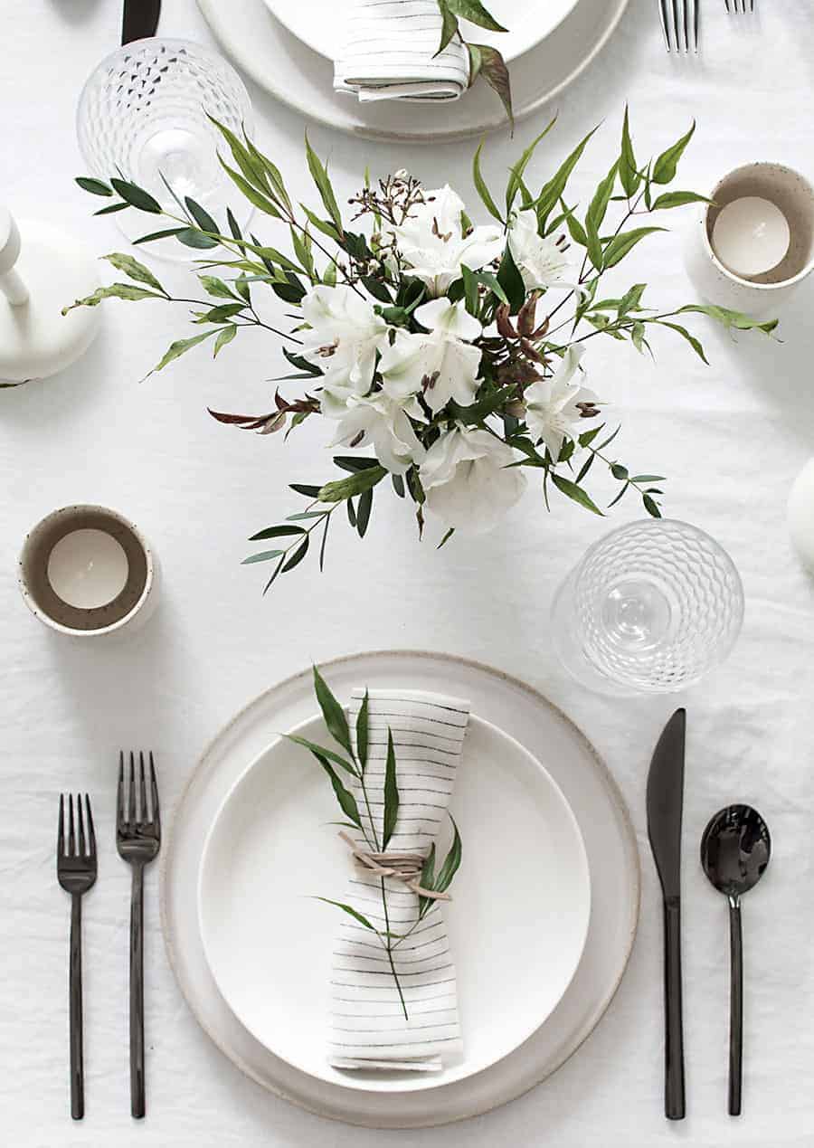 white elegant dining table setting decor ideas with Cutlery, plates, flower vase, napkins and glasses