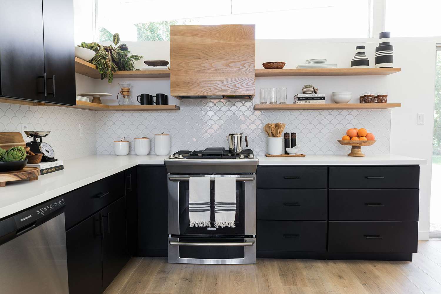 black kitchen with silver appliances, shelves and wooden floor