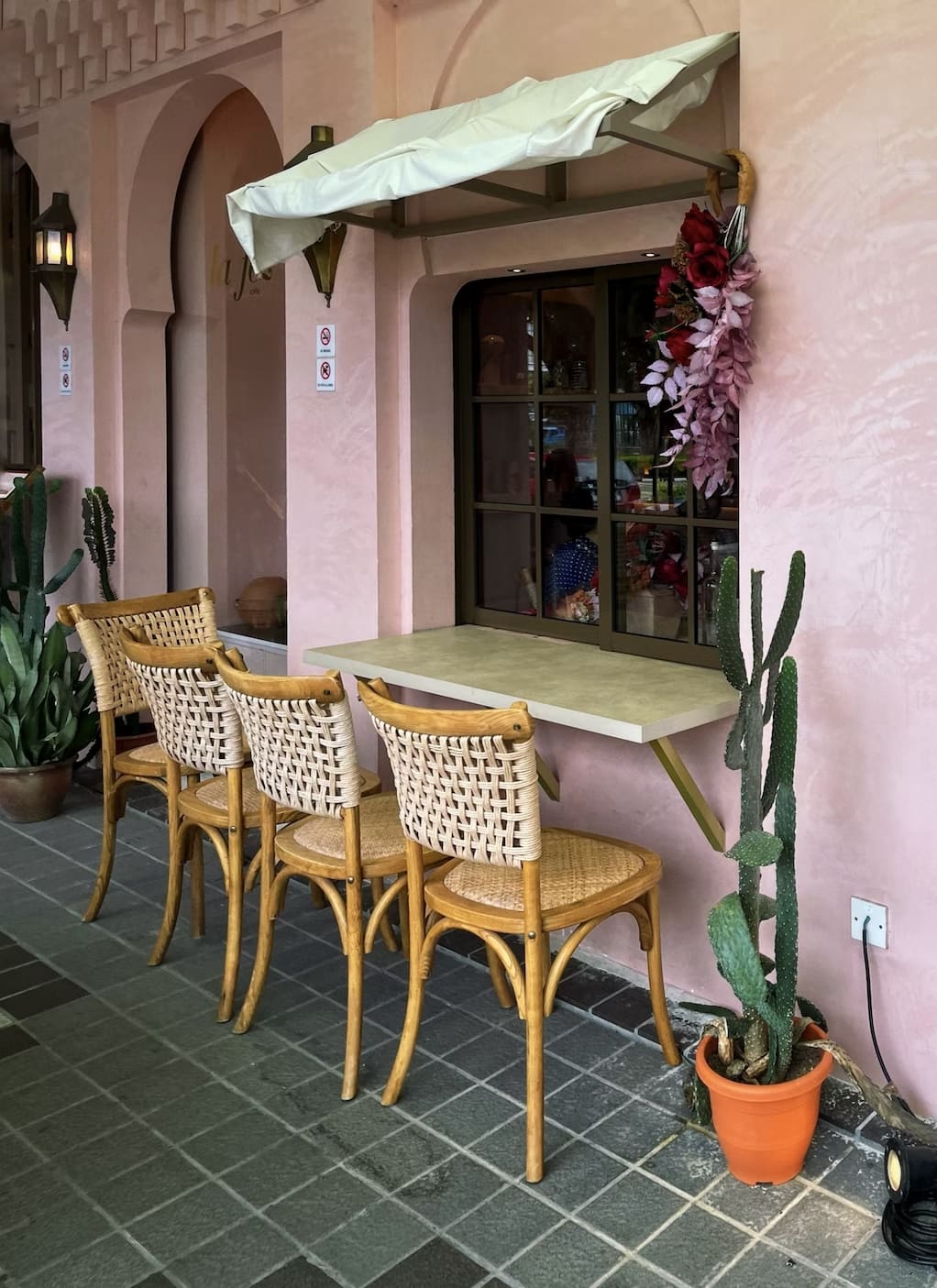 cacti placed near the window, wooden chairs, pink walls, floor tiles