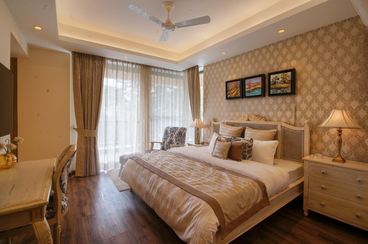 bedroom with brown interiors, bed, side table, lamp and fan