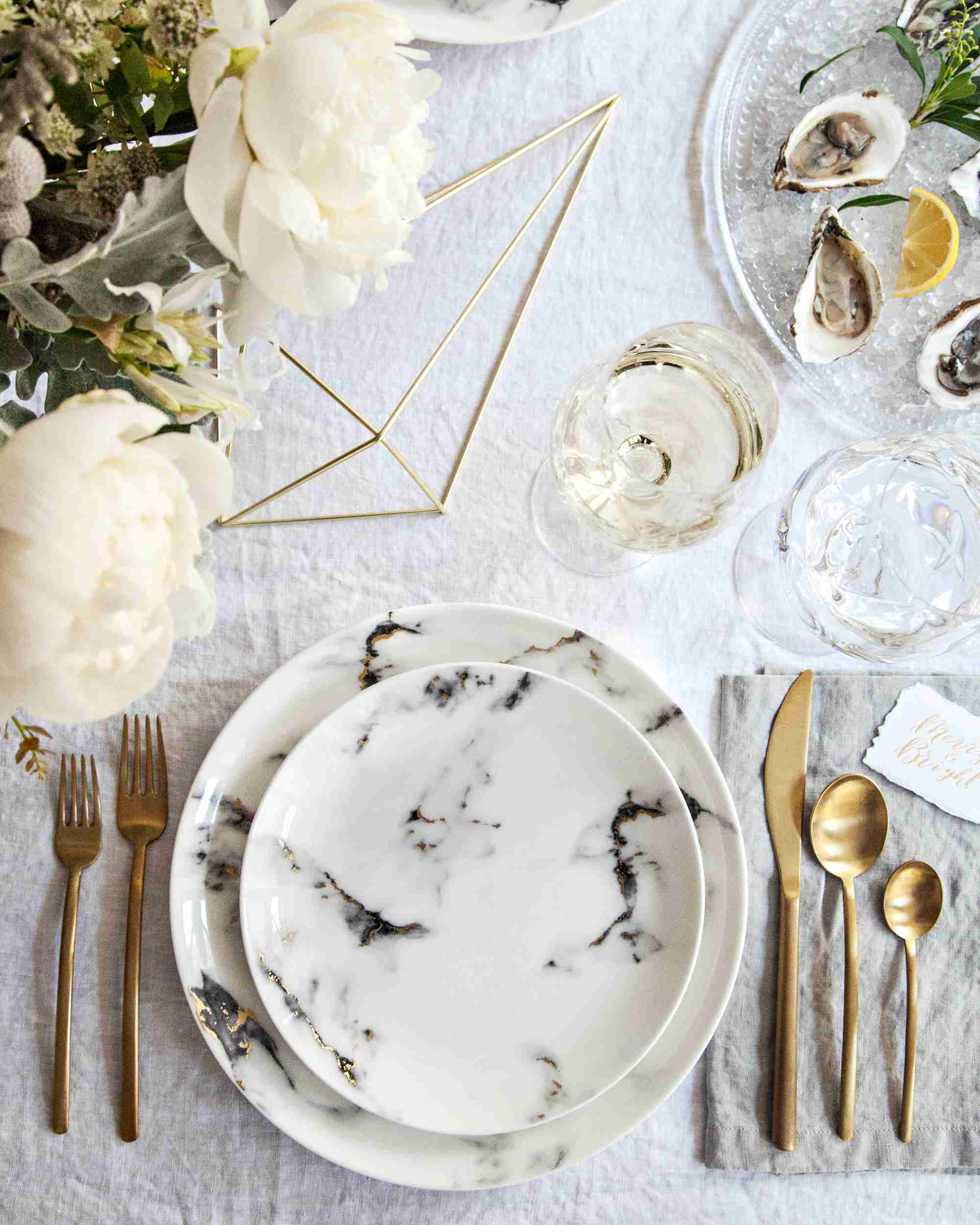 white dining table with Cutlery, plates, napkins, floral decorations and glasses