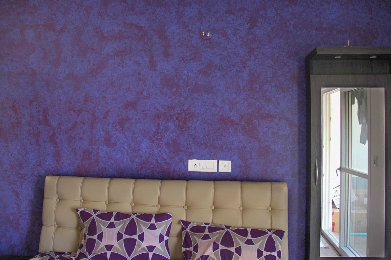A PURPLE WALL WITH A DOOR AND BED.