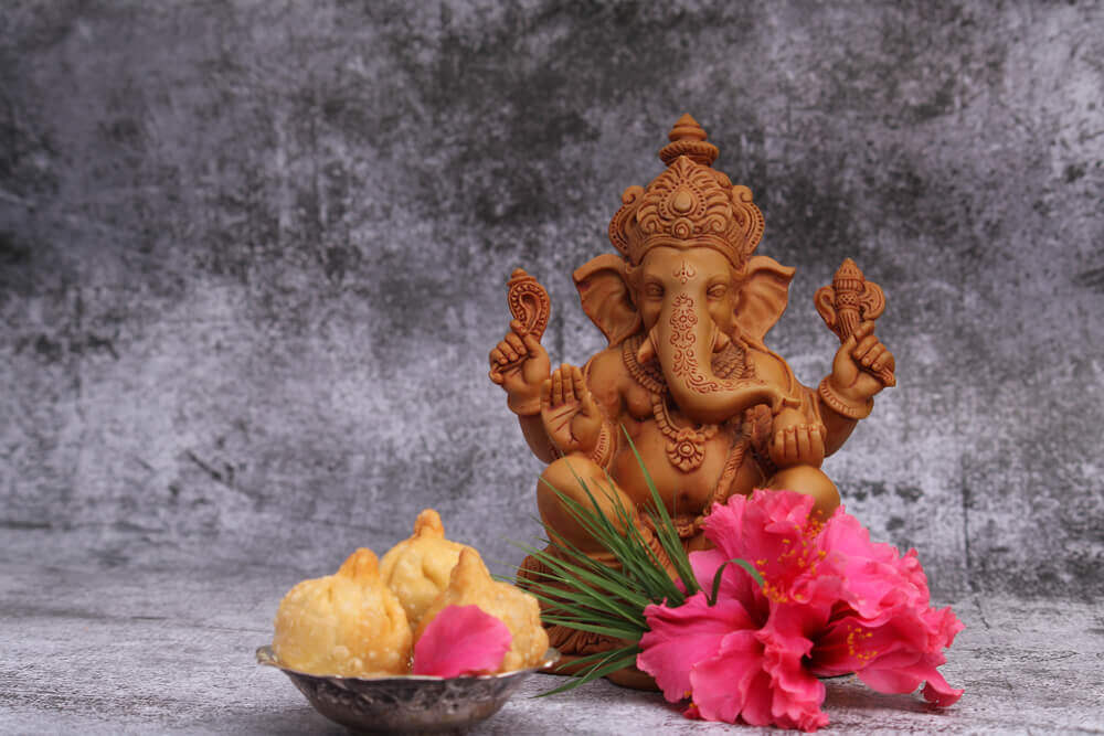 Ganapati statue in a seating posture, shoeflower placed in front of idol, modak placed in a bowl