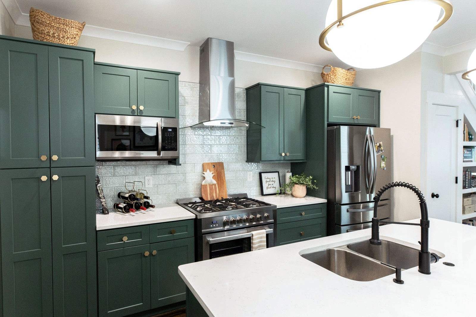 green kitchen cabinets with appliances, chimney, sink, white countertops, and fridge