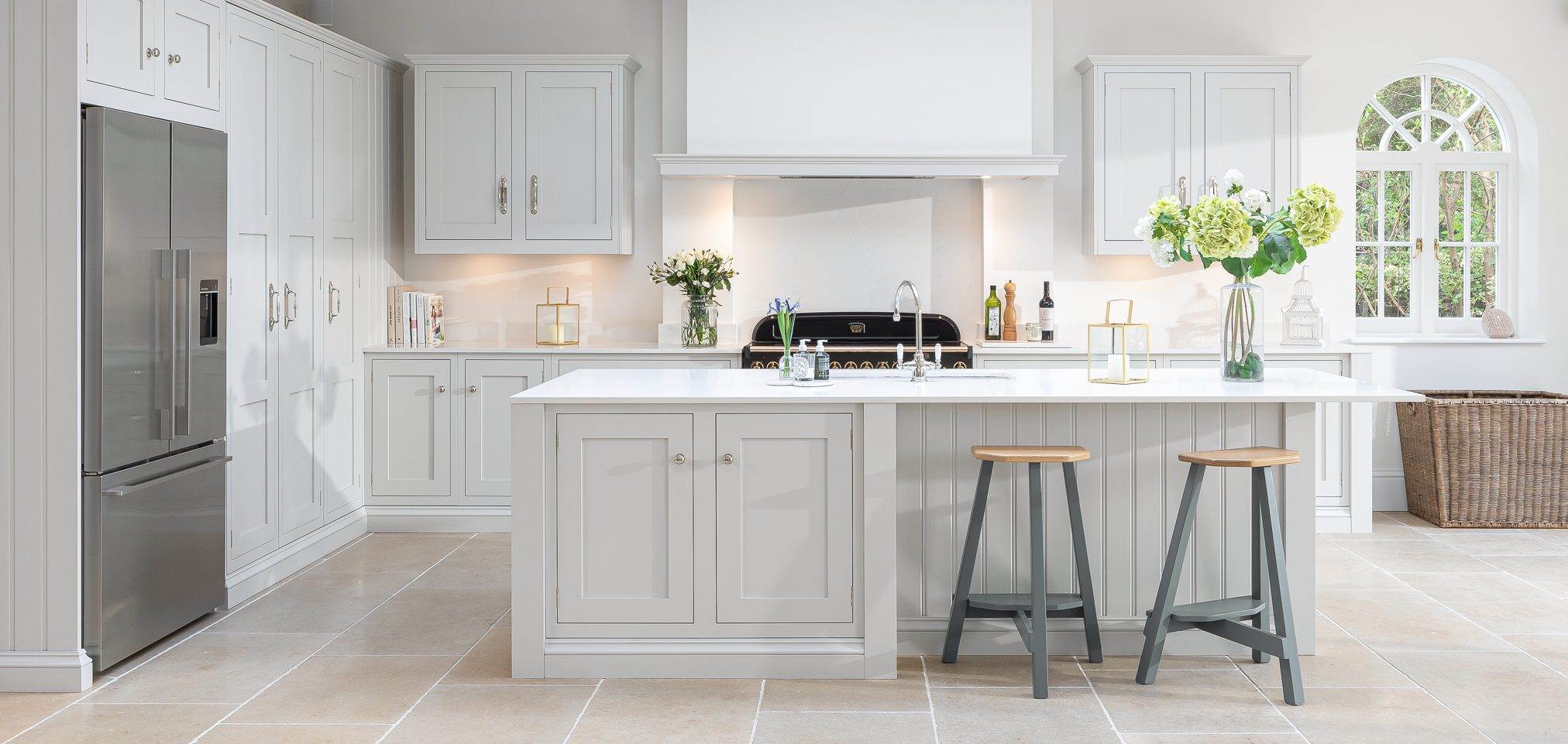 grey kitchen with silver apppliances, white kitchen island, chairs and sink