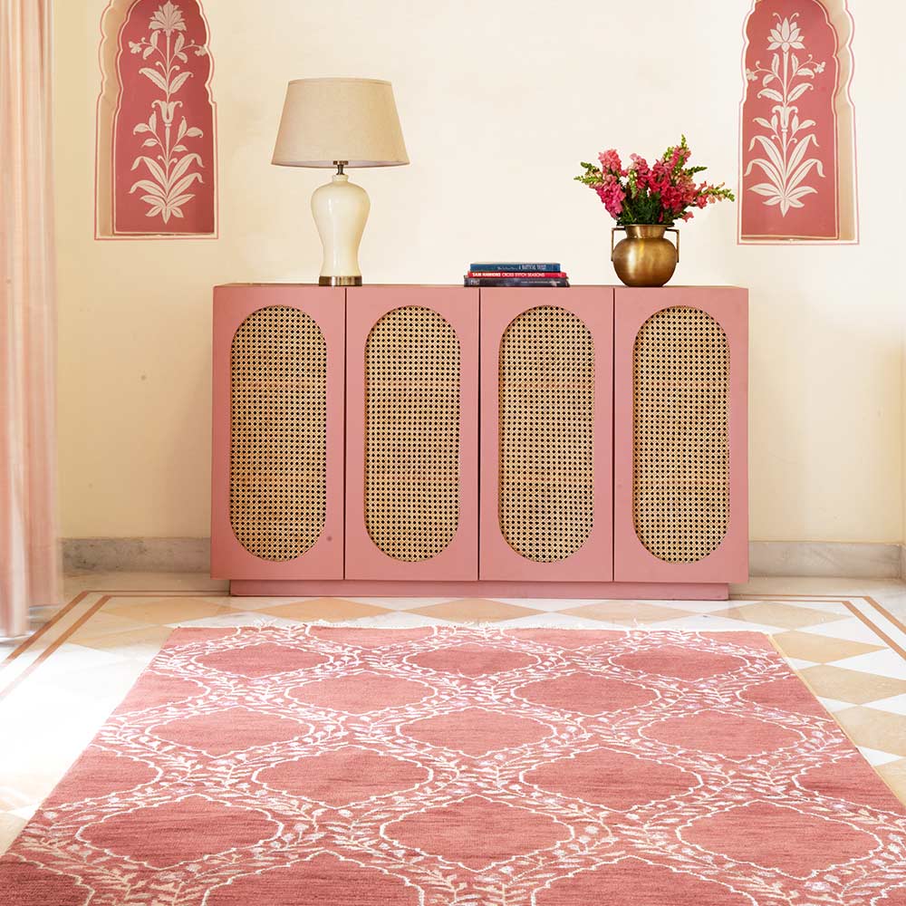gorgeous pink coloured hand knotted carpet, placed in a living room, storage cabinet, lamp and flower vase placed on cabinet