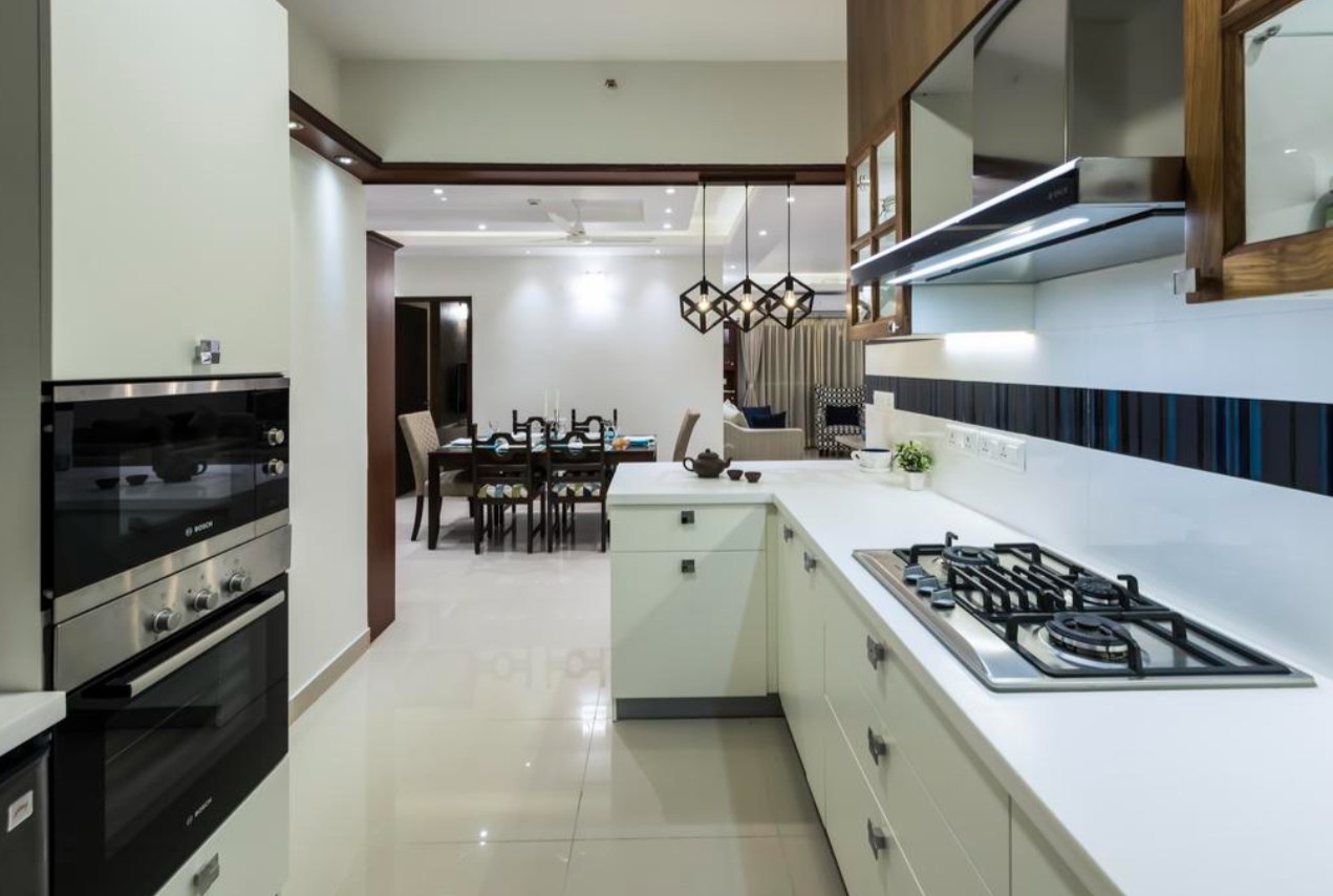 white kitchen with a view of the dining table chairs, hanging lights and white cabinets