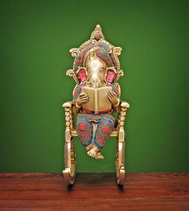 multicoloured ganpati statue seating on a rocking chair, placed on a table for home decor, metal statue