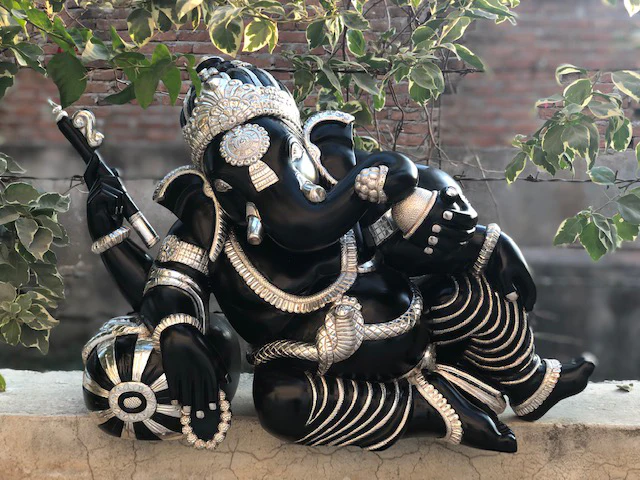 Ganapati murti or photo in a resting or reclining position, handcrafted in teak wood and covered with pure silver sheet, intricated with elegant carvings