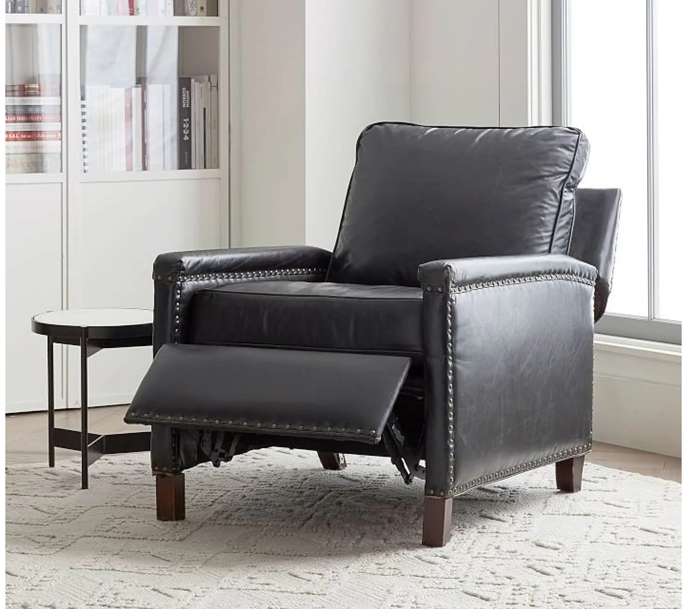 black recliner seat, placed in a hall, a table placed beside the recliner, black coloured recliner