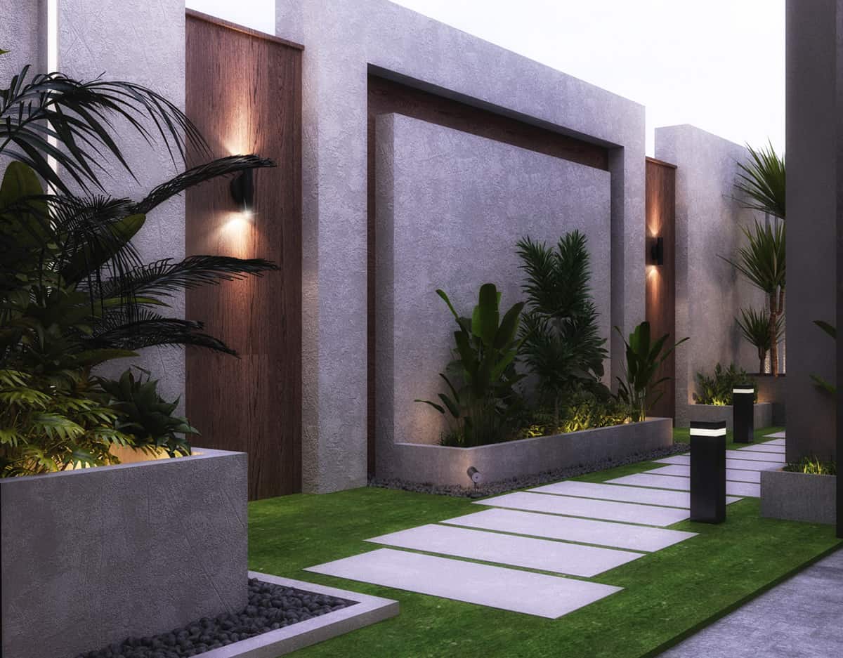 A large compond wall with gray concrete texture and plants.