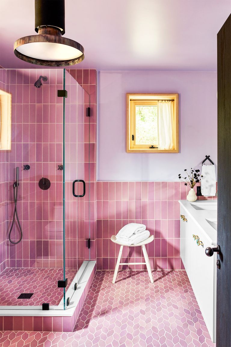 pink washroom with tiled floors and walls, white chair, shower and white cabinet with washbasin