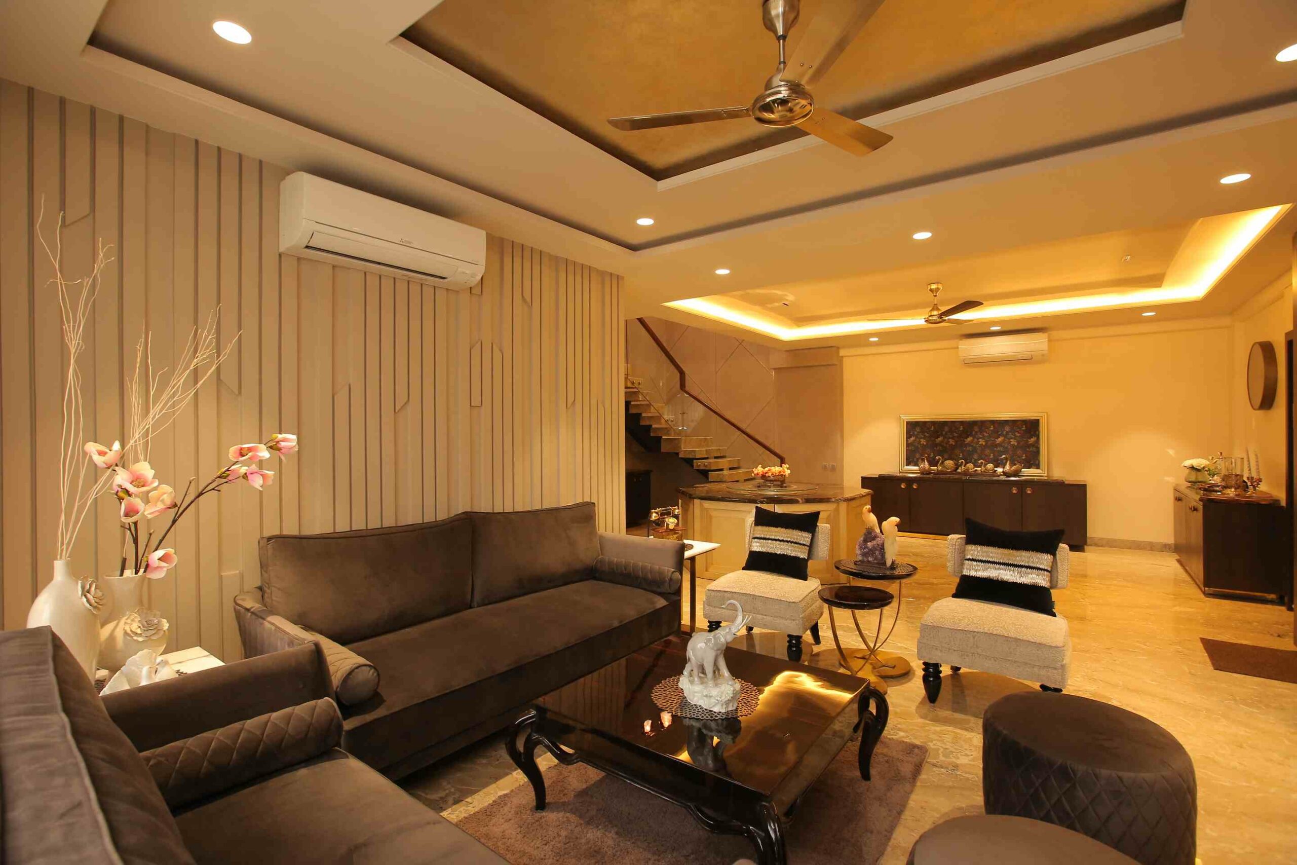 Luxury living room with sofa set and black table with false ceiling lights, fan and stairs
