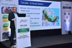 Mr. Pranesh Chhibber, Country Director, Canadian Wood standing behind a white podium giving presentation in a hall in a seminar about wood in manufacturing promoting the use of sustainable wood and timer in making woodwork, wooden products and wooden furniture